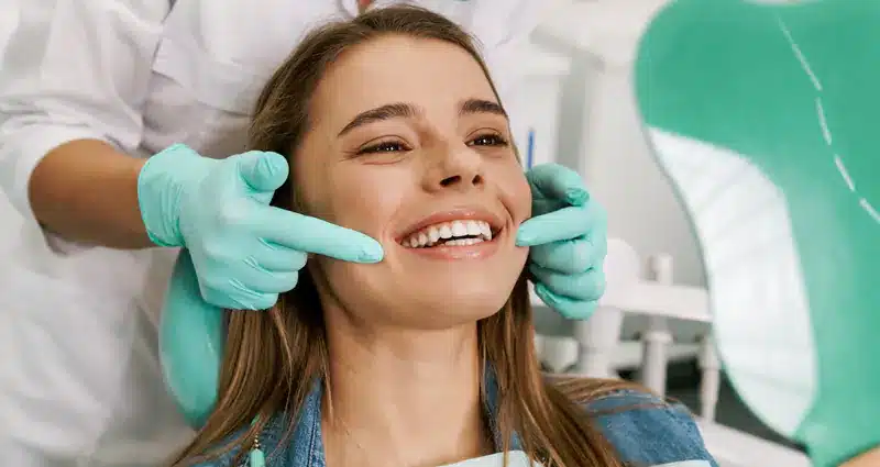 Joven mostrando su dientes después de un procedimiento con carillas dentales - Coomeva Salud Oral